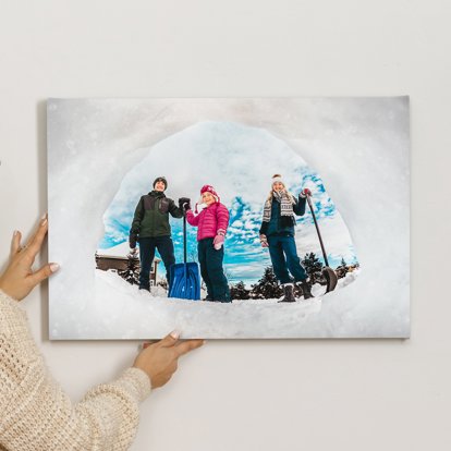 Canvas print featuring a photo taken from inside a snow fort looking out to a family in winter gear and holding shovels. 