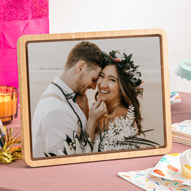 A Tabletop Framed Metal Print displayed on a table featuring a photo of a bride and groom