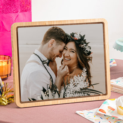 A metal print framed in a bamboo stand featuring a wedding picture of a bride and groom.