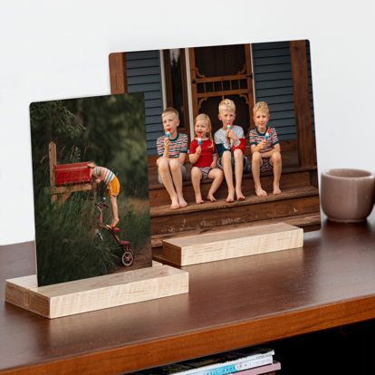 two tabletop metal prints with family photos resting on a desktop, showing two different size prints.