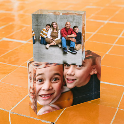 Two stacked mini acrylic blocks. On top is a 2x2" mini acrylic block featuring a family of four sitting in front of a concrete wall. The bottom 2x3" acrylic block features a close-up of the two young brothers. 