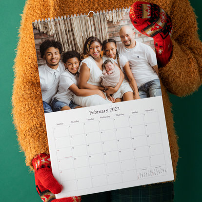 A customer holding a wall calendar that has binding on top to showcase how it would hang on a wall