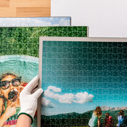 A close up of the hand of an Mpix worker doing a final inspection on a group of printed photo puzzles.