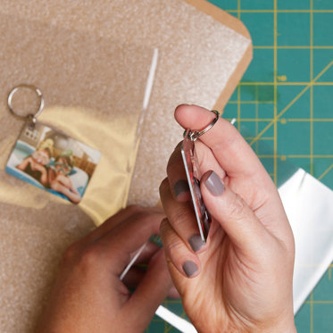 a worker inspects the quality of a metal photo keychain after it is printed