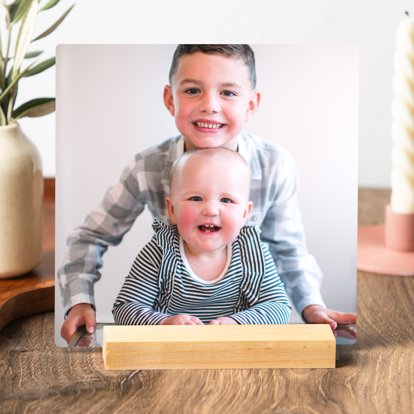 A tabletop metal print featuring a photo of a young boy with his baby sister.