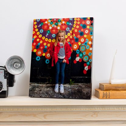 a foam mounted print of a young girl standing in front of a brightly colored pinwheel patterned wall resting on the counter 