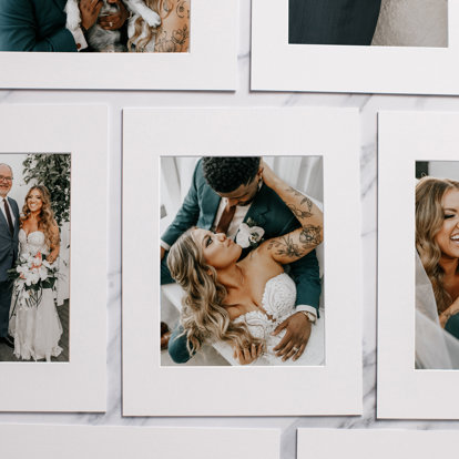 A group of matted prints with wedding images spread out on a desktop.