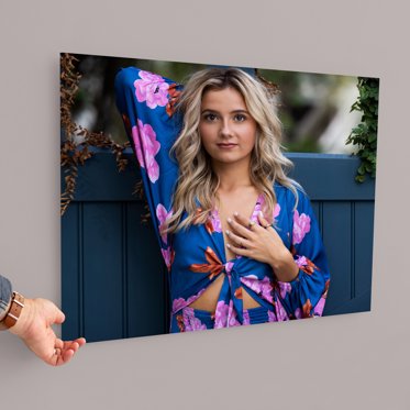 An acrylic photo print from Mpix showing a girl wearing a blue dress with pink flower accents in front of a blue fence taken for her senior photos. 