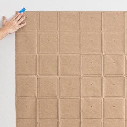 Multiple grid paper sheets taped to a wall in a rectangular shape. 