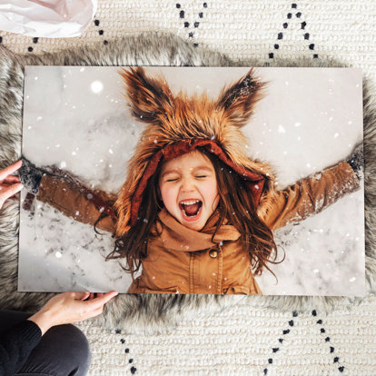 A 20x30 photo print featuring a young girl in her warmest winter coat making a snow angel.