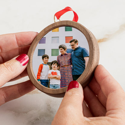 Hands holding a circle shaped framed ornament featuring a photo from a family portrait session.