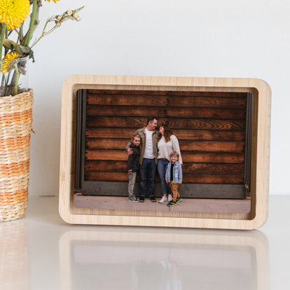 A horizontal oriented metal photo print with rounded corners framed with a tabletop bamboo float frame.