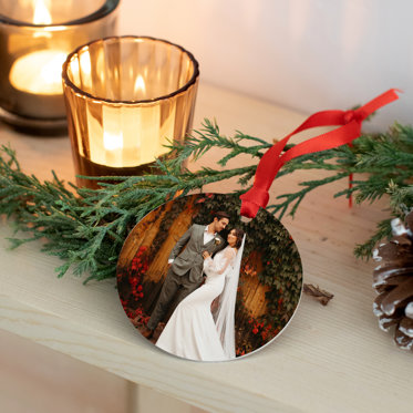 A circle metal holiday ornament featuring a wedding photo of a bride and groom.