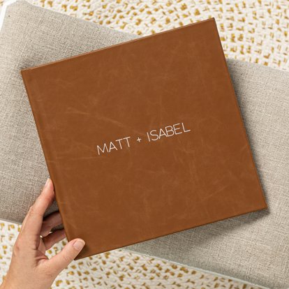 A closed photo album with a clay brown leather cover and names debossing in gold foil.