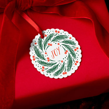 A circular photo ornament with a wreath of holly and the word 'Joy' in the middle. 
