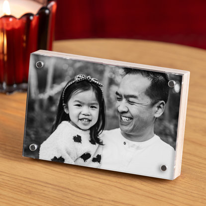 A Birch Photo Block featuring a print of a father and daughter that is displayed on a table with candles in the background.