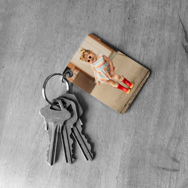 Metal Keychain featuring a photo of a toddler sitting on the steps in front of her house with bright red boots and sunglasses.