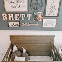 A nursery collage wall with a name sign, framed prints and a crib