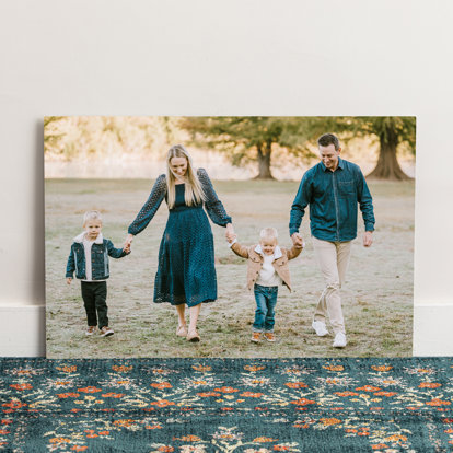 A large metal print of a young couple and their two toddlers boys walking alongside each other holding hands.