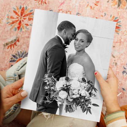 Hands holding a black & white photo print of a bride and groom on their wedding day.