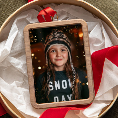A rectangular shaped framed photo ornament in a gift box. The photo is of a girl in a 'snow day' sweatshirt wearing a stocking cap.