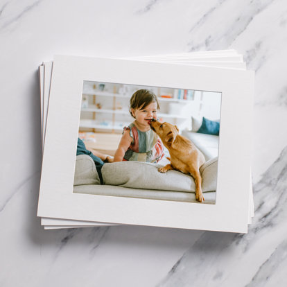 A stack of matted prints sitting on a desktop.