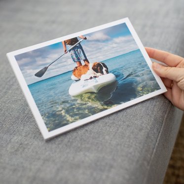 A softcover photo book with a single image cover being held showing summer memories.