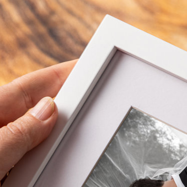 An up-close look at the thick white mat and flat white frame of a tabletop framed photo.