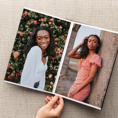 An open signature photo album in a vertical orientation showing two photos of a young girl posing for her senior portraits. 