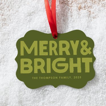 A holiday ornament with a luxe die cut shape, a dark green background, and light green text that reads "Merry & Bright The Thompson Family, 2025"