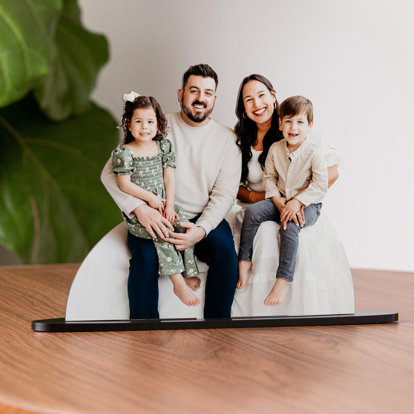 A photo cutout of a couple and their two young kids sitting on their laps. 