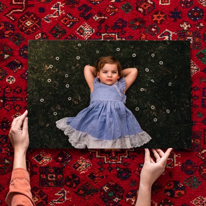 An acrylic photo print laid out on the ground featuring a family portrait of a young girl. 