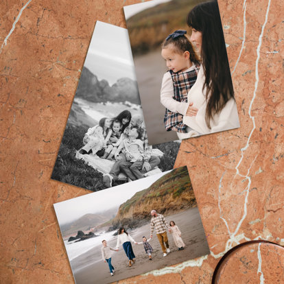 Three photo prints laid out on a counter. The photos feature shots from a family portrait session taken on a beach in the fall.