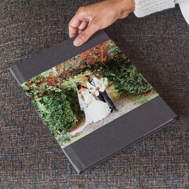 A photo book with a graphite linen cover and skinny dust jacket featuring a photo of a bride and groom outside. 