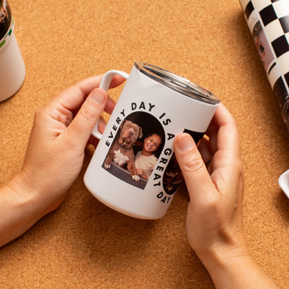 Hands holding a stainless steel photo travel mug featuring pictures of a girl and her dog with the text 'Every day is a great day.'