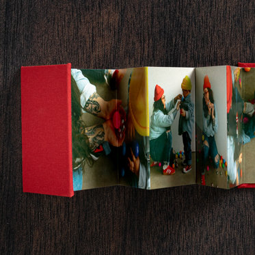 Accordion mini photo book from Mpix with a red cloth cover and christmas photos in the middle.