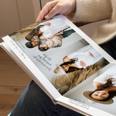 A person holding an open guest book that features photos and signatures.
