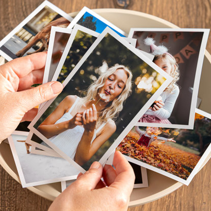 A close up of hands holding a batch of 4x6 Photo Prints from Mpix with various images and white borders around the photos.