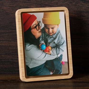 A tabletop framed metal print from Mpix displayed on a desk and featuring an images of a mother and baby.