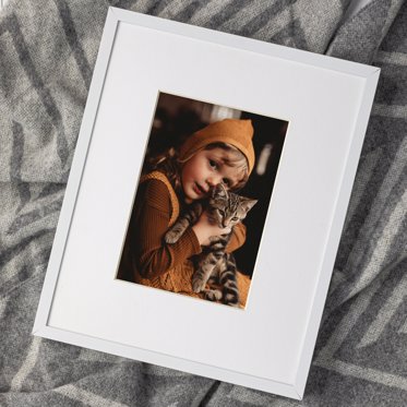 photo print of a young kid and his pet kitten shown with a large white window mat and a thin white frame 