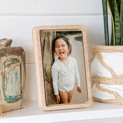 A vertical oriented metal print with a standing bamboo float frame on a shelf.