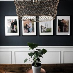 Framed family portraits on a navy wall above white wainscoting