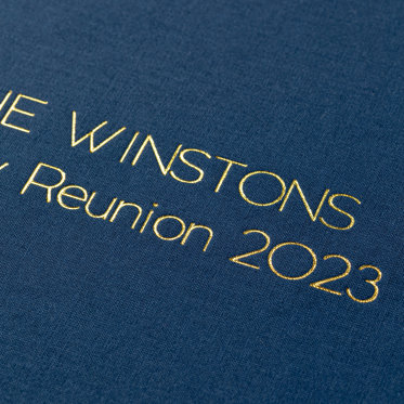 A close-up image of a guest book with a Windsor linen cover and gold foil debossing.