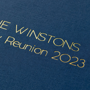A close-up image of a guest book with a Windsor linen cover and gold foil debossing.