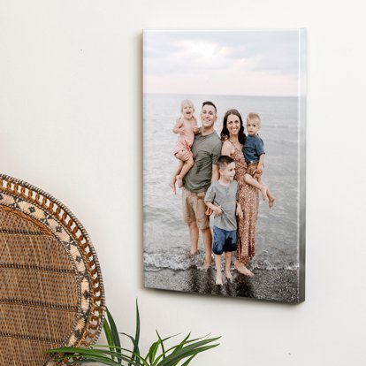 A canvas print hanging on the wall featuring a photo of a couple and their three young kids standing on the beach. 
