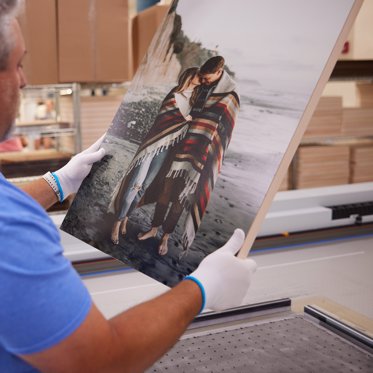 a worker inspects a wood photo print for quality at the Mpix lab