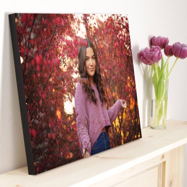 Standout photo print from Mpix resting against the wall on a mantle next to a vase of purple flowers with a senior portrait of a girl surrounded by purple flowers.