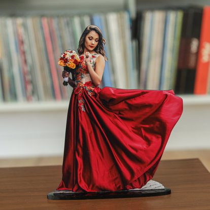A statuette photo cut out from Mpix featuring a young woman in a flowing red dress holding flowers, the cut out follows the shape of her dress billowing in the wind. 