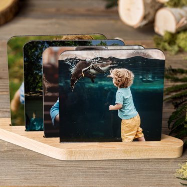 A set of four personalized coasters from Mpix in a wooden stand for display, the first photo is of a kid at the zoo.