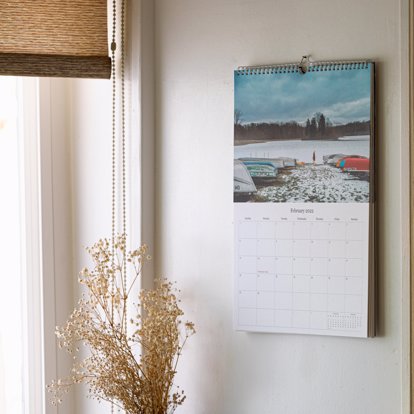 An example of a wall calendar hanging on a wall using the binding on top.